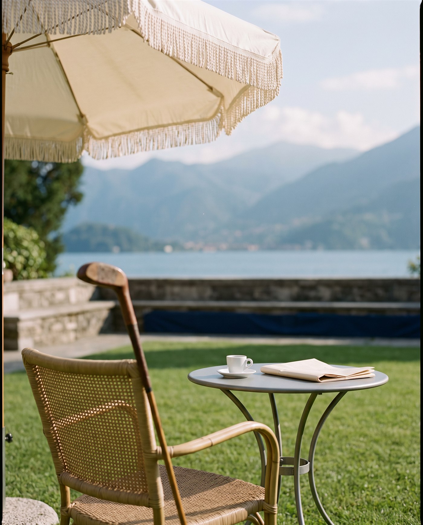 Un tavolino con espresso e giornale in una terrazza sul lago.